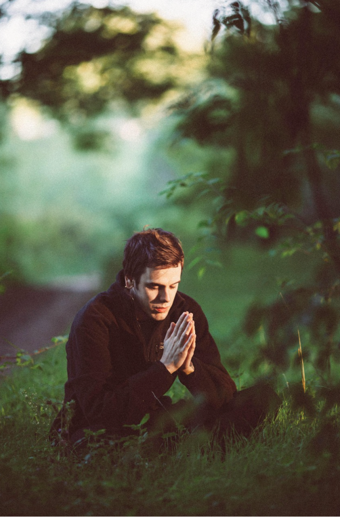 A peaceful man meditation and relaxation in nature at sunrise, surrounded by misty mountains and glowing light, symbolizing inner calm and mindfulness in a hectic world.