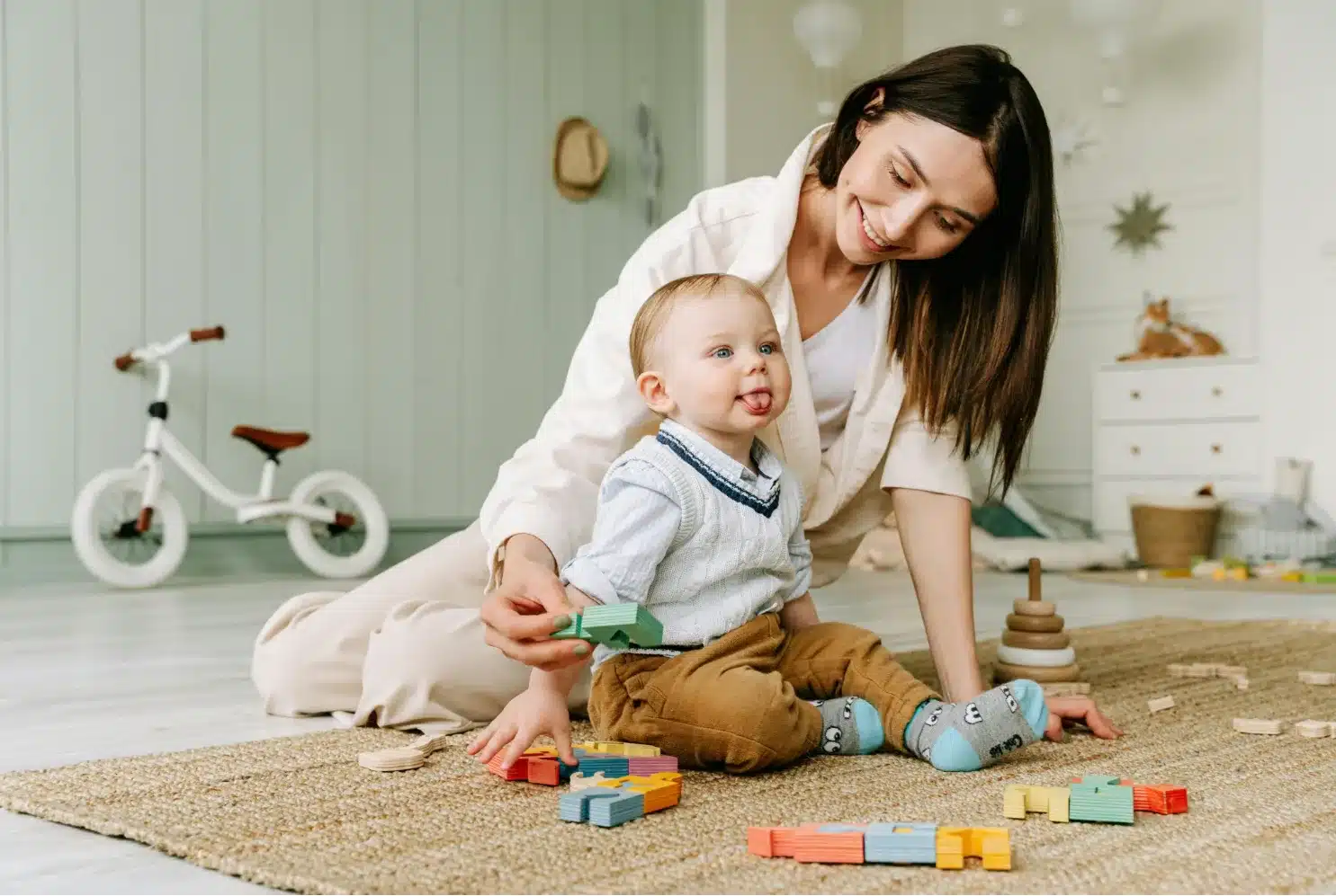 Caregiver using transformative nanny techniques while playing with toddler and colorful alphabet blocks