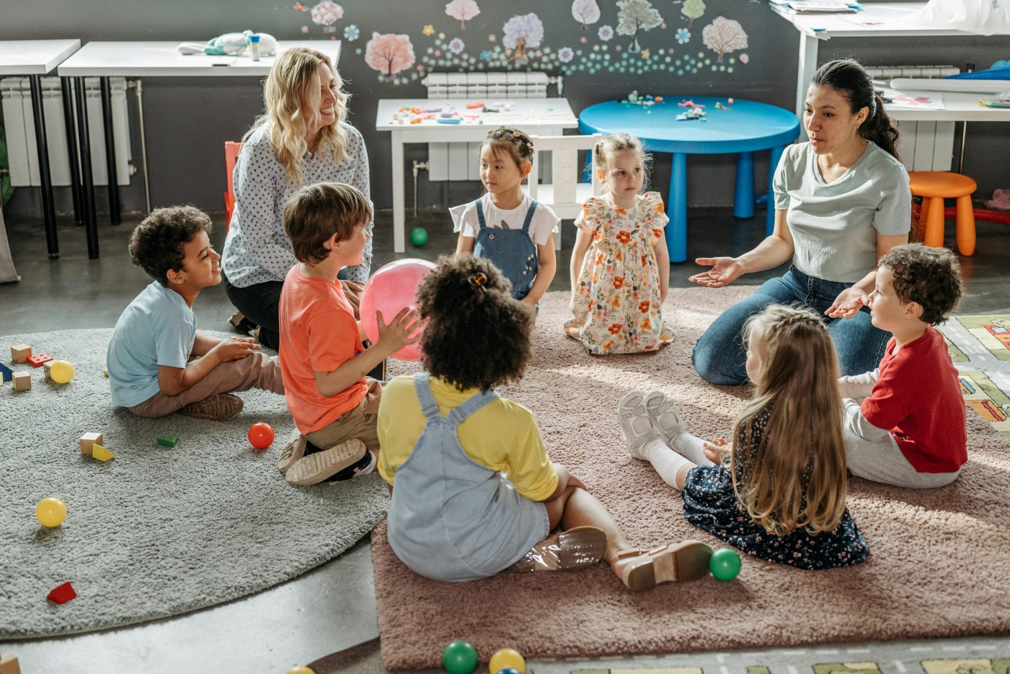 Childcare basics provider reading to young children in safe nursery environment demonstrating nurturing childcare basics and early childhood development