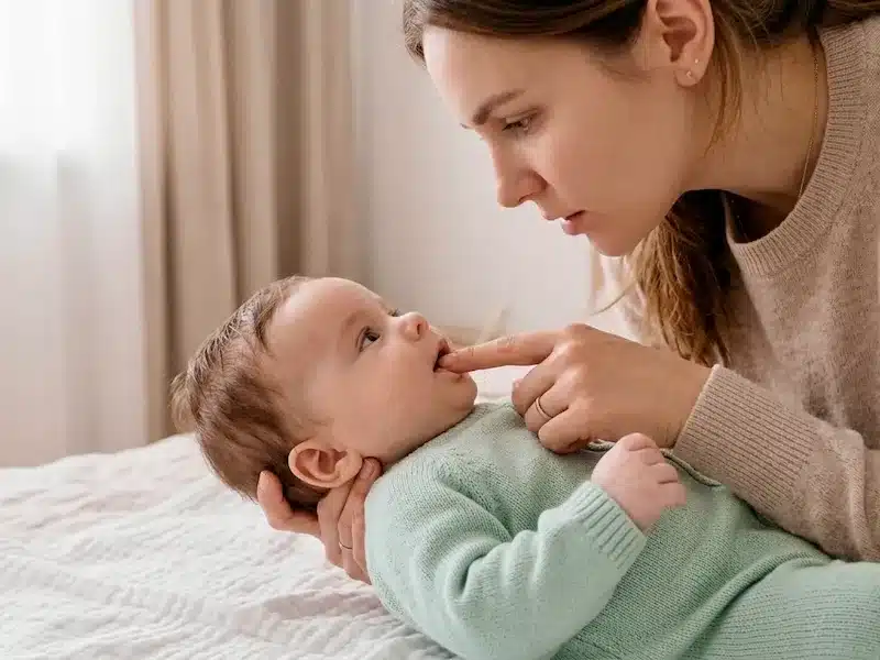 Mother checking baby's mouth for dryness, one of the earliest baby dehydration signs