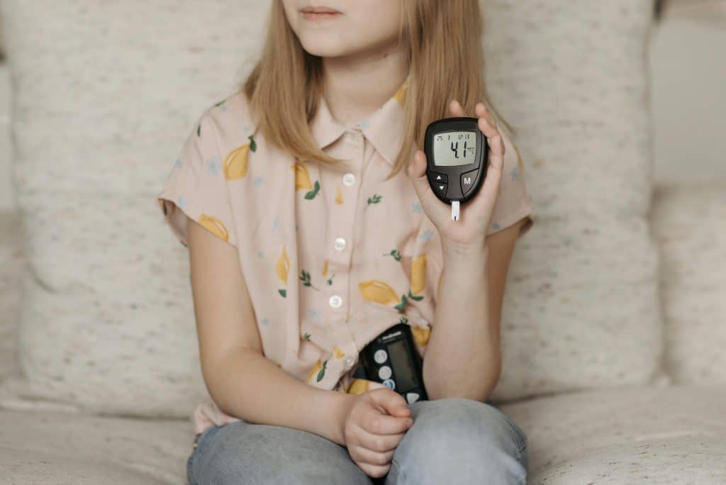 diabetes symptoms in children - child holding glucose meter for blood sugar monitoring