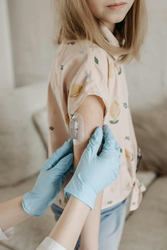 diabetes in children - healthcare professional applying glucose sensor on child's arm